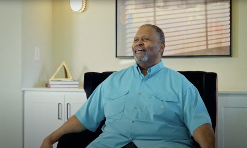 a man sitting in a chair wearing a blue shirt