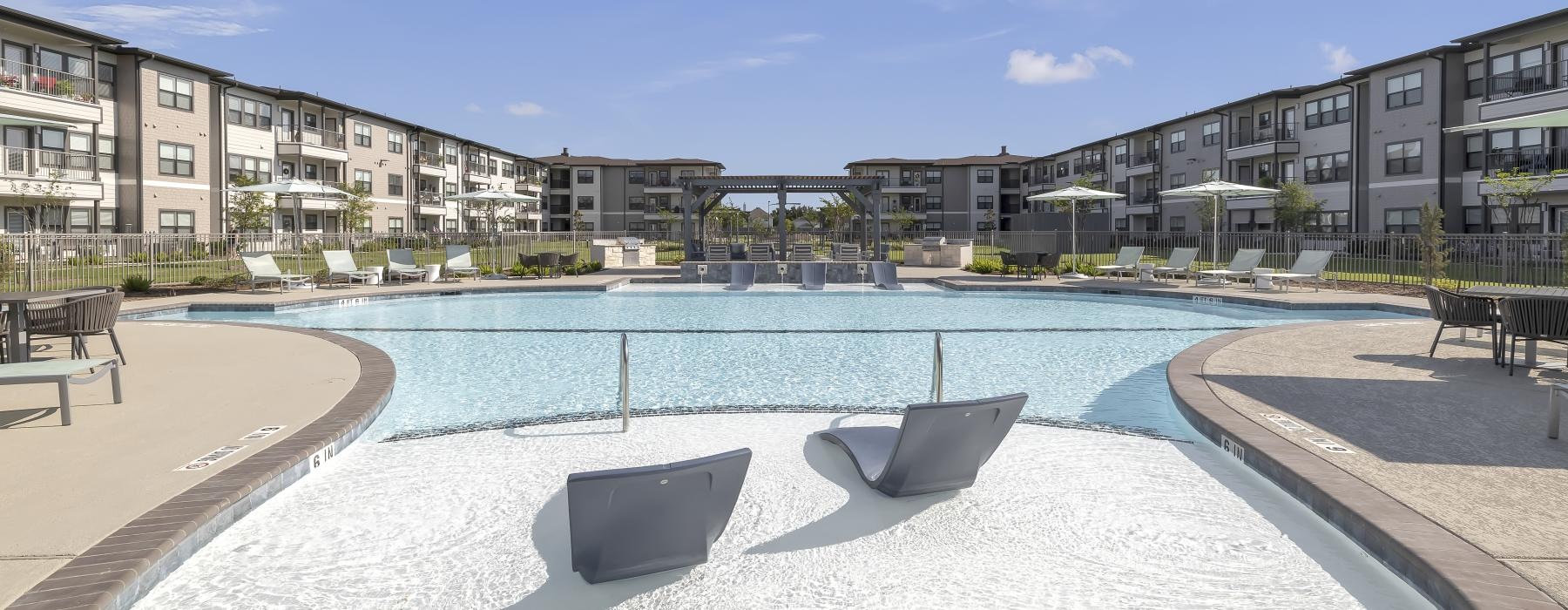 a swimming pool with chairs and a building in the background