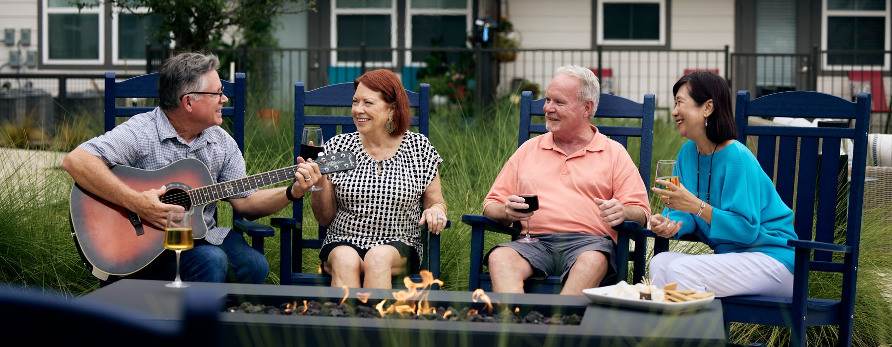 people sitting around fire and a man playing a guitar